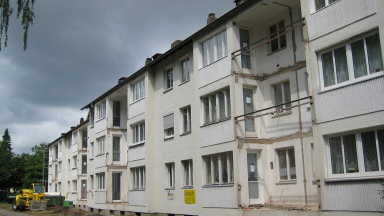 Ein Vorher-Bild eines sanierungsbedürftigen alten Gebäudes in der Gerhart-Hauptmann-Straße 1-11. Die einst weiße Grundierung ist durch die Zeit verfärbt worden.
