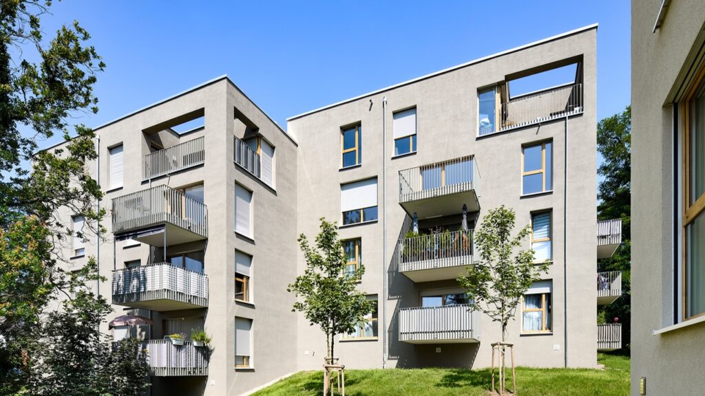 Vorher-Bild der historischen Hornschuchvilla in der Mayer-Franken-Str. 38. Die Fassade ist von einem grauen Beigeton geprägt, wobei die Fenster ebenfalls gelbe Akzente aufweisen. Viele Balkone sind sichtbar, darunter zwei eingebaute Balkone.